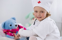 Cute little girl dressed as doctor playing with toy
