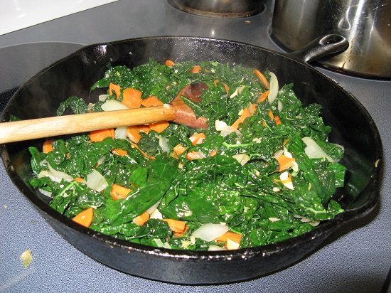 Black pan with fresh vegetables and wooden spoon