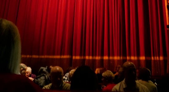 move audience looking at red curtain
