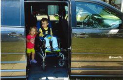 Payton sits in his wheelchair inside a van equipped with a ramp.