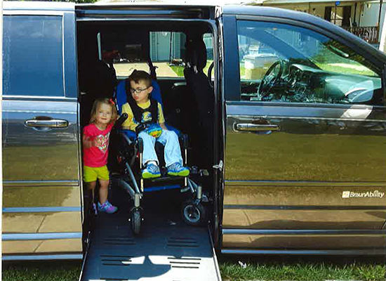 Payton sits in his wheelchair inside a van equipped with a ramp.