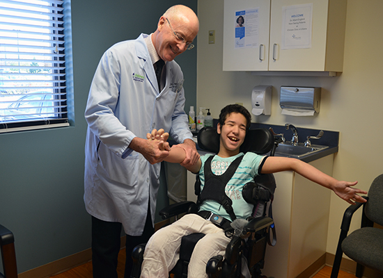 Dr. Keith Gabriel smiles as he holds patient, Bayan's hand