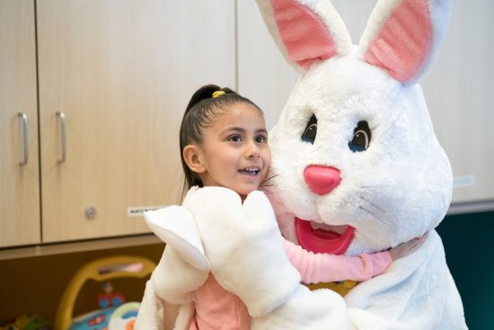 Little girl smiles while hugging the Easter Bunny