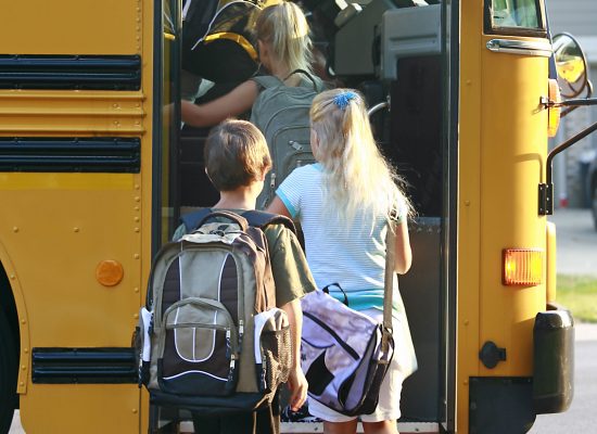 Three students boarding a school bus