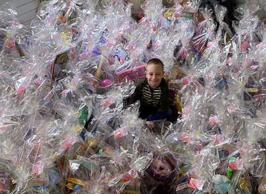 Axel Johnson smiles as he sits surrounded by hundred of wrapped Easter basket donations