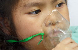 Young girl holding an oxygen mask up to her face