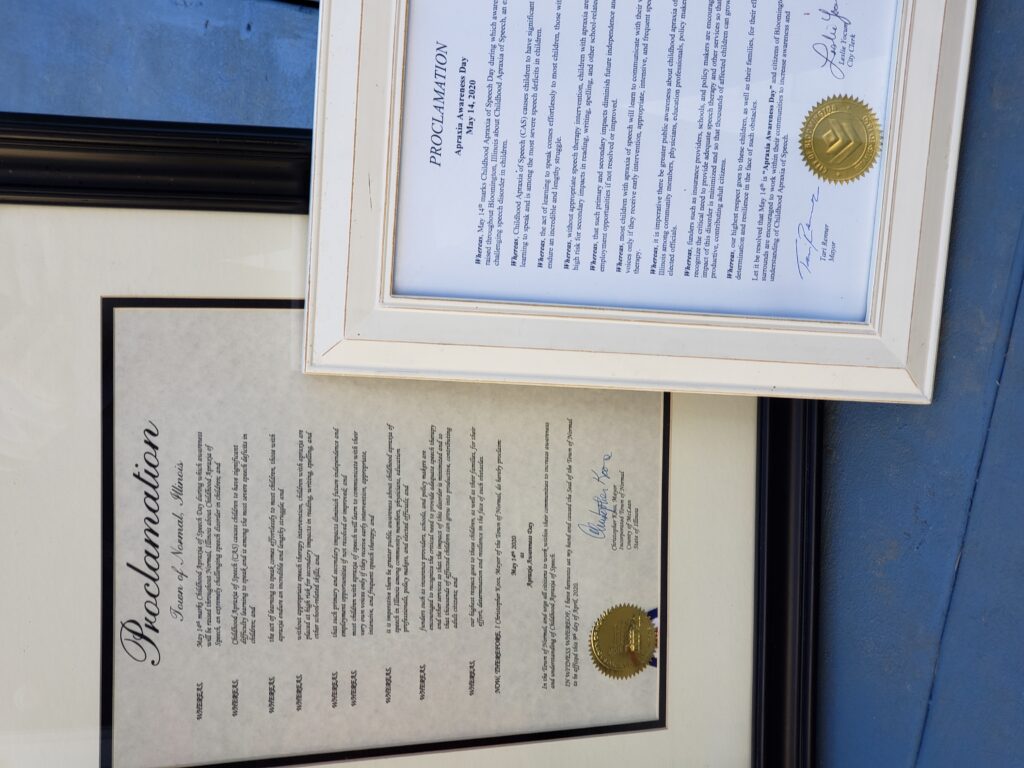 Framed Apraxia Awareness Day Proclamations for the city of Normal and the city of Bloomington.