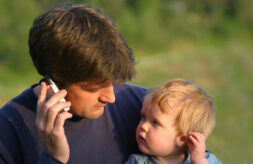 A young son mimics his father who is talking on his mobile