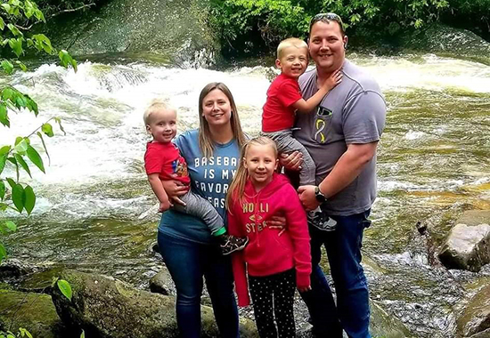 The Miller family poses together outside in front of a stream.