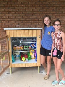 Emma Wiker and her sister, Ellen, stand beside the pet pantry they opened in Athens, Ill.