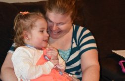 A mom holds her young daughter with complex medical needs and smiles at her