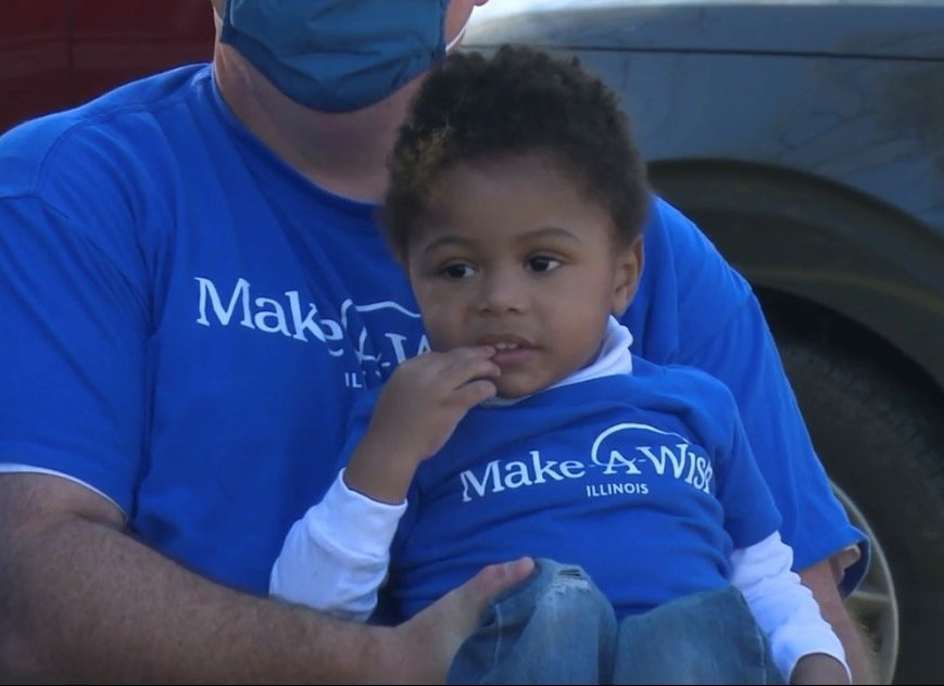 3-year-old T'Aubrae smiles as he watches a special community parade in his honor