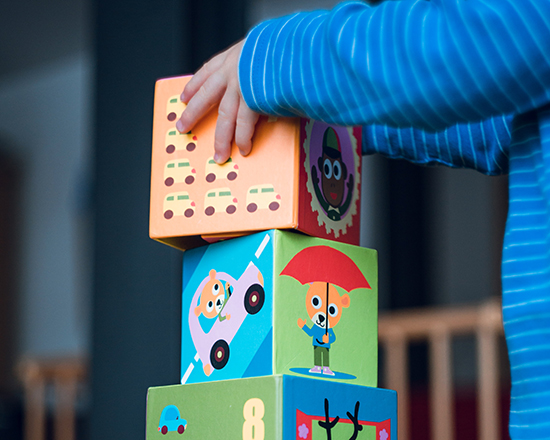 close-up of a child's hands stacking large blocks