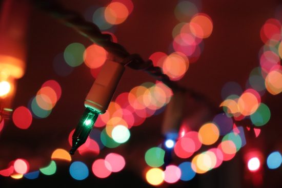 close-up of a green Christmas light bulb with multiple colored Christmas lights in the background