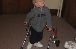 Collin M as a toddler smiling and using his walker