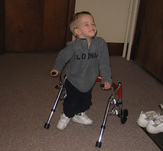 Collin M as a toddler smiling and using his walker