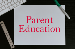 The text "Parent Education" on a sheet of paper next to a computer keyboard, ruler and marker