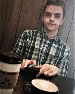 Collin M looking at the camera and enjoying coffee