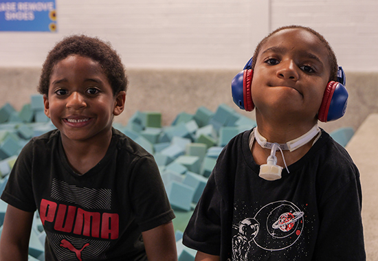 DSCC participant Dominic Garvin, 10, wears noise-cancelling headphones as he sits beside his younger brother on the edge of a foam block pit