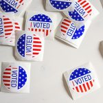 Red, white and blue "I Voted" stickers scattered on a white background