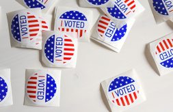 Red, white and blue "I Voted" stickers scattered on a white background