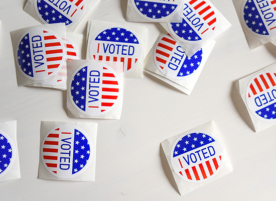 Red, white and blue "I Voted" stickers scattered on a white background