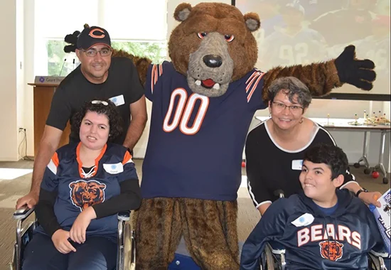 Daniel and Diana Barraza and their parents, Anita and Jose, pose with the Chicago Bears mascot while wearing Chicago Bears jerseys