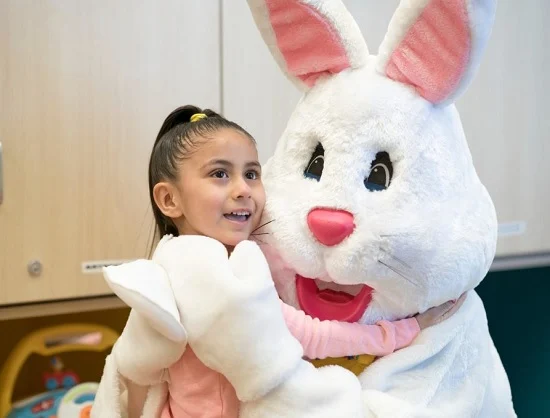 Little girl smiles while hugging the Easter Bunny