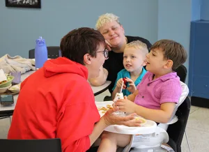 Kelly Lane plays with her son Casper, 4, while her other son Courtland, 5, and partner Crystal Harris look on and smile during lunchtime at the Institute.