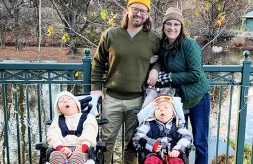 Erica Stearns and her husband stand arm-in-arm between their children Margot and Caratacus Stearns who are in medical wheelchairs while the family enjoys time outdoors