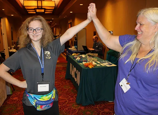 DSCC participant Vera Lindquist gives her grandmother, Cheryl, a high five during the 2023 Illinois Statewide Transition Conference