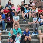 A group photo of Institute participants and their families on the dorm steps.