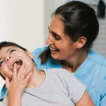 A nurse holds a laughing boy with cerebral palsy