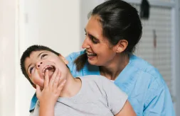 A nurse holds a laughing boy with cerebral palsy