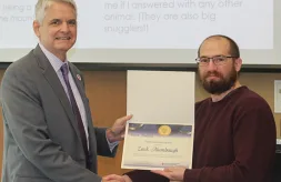 IT Support Associate Zack Alumbaugh receives his Award of Merit nomination certificate from Executive Director Thomas F. Jerkovitz.