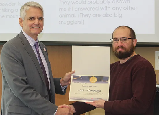 IT Support Associate Zack Alumbaugh receives his Award of Merit nomination certificate from Executive Director Thomas F. Jerkovitz.