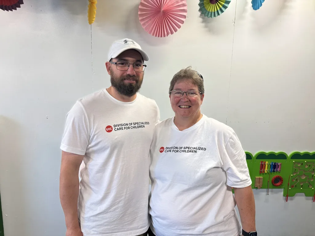 Zack and Stephanie Alumbaugh smile together while working at the Sensory Station at the 2024 Illinois State Fair.