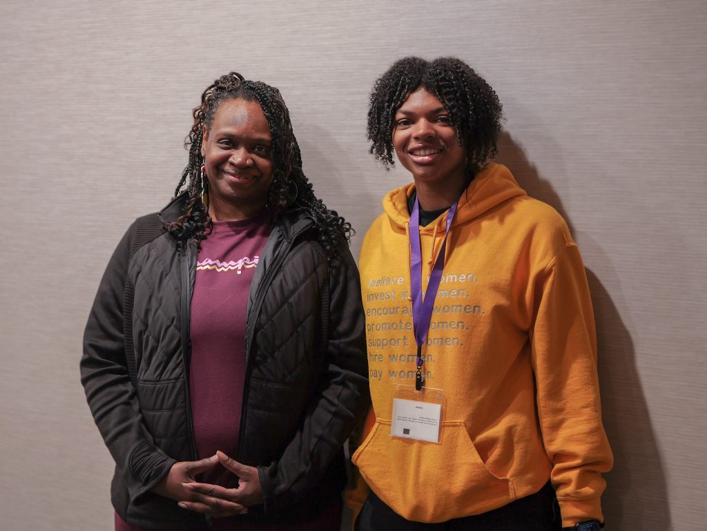 A teenage DSCC participant stands next to her mom for a posed photo in the interview meeting room.