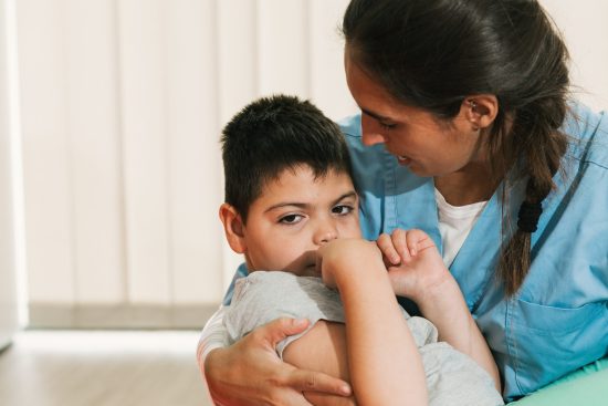 A nurse holds a little boy with cerebral palsy