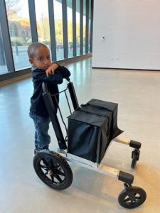 DSCC participant Dominic Garvin stands next to a cart designed to carry his ventilator and easily move beside him. Dominic's mom, Aurea, worked with the Mechanical Engineering class at the University of Illinois Urbana-Champaign to design the cart especially for his needs.